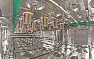 Blick in die vierbahnige Längsläufer-Becherfüllanlage FOODLINER 6.000 für die Abfüllung von fruchtunterlegten und geswirlten Milchprodukten.