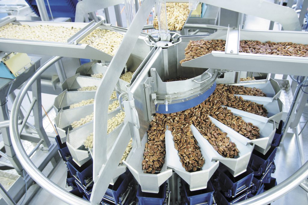 Unterschiedliche Nusssorten und sehr klebrige Trockenfrüchte werden verwogen und verpackt.