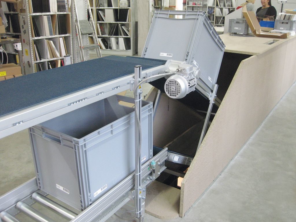 Steigförderband zum Transport der Kommissionierboxen über zwei Etagen hinweg