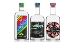 Drei Spirituosenflaschen mit bunten Etiketten im Metallic Look