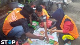 Drei Menschen sortieren für Projekt STOP in Indonesien Verpackungsmüll aus Plastik