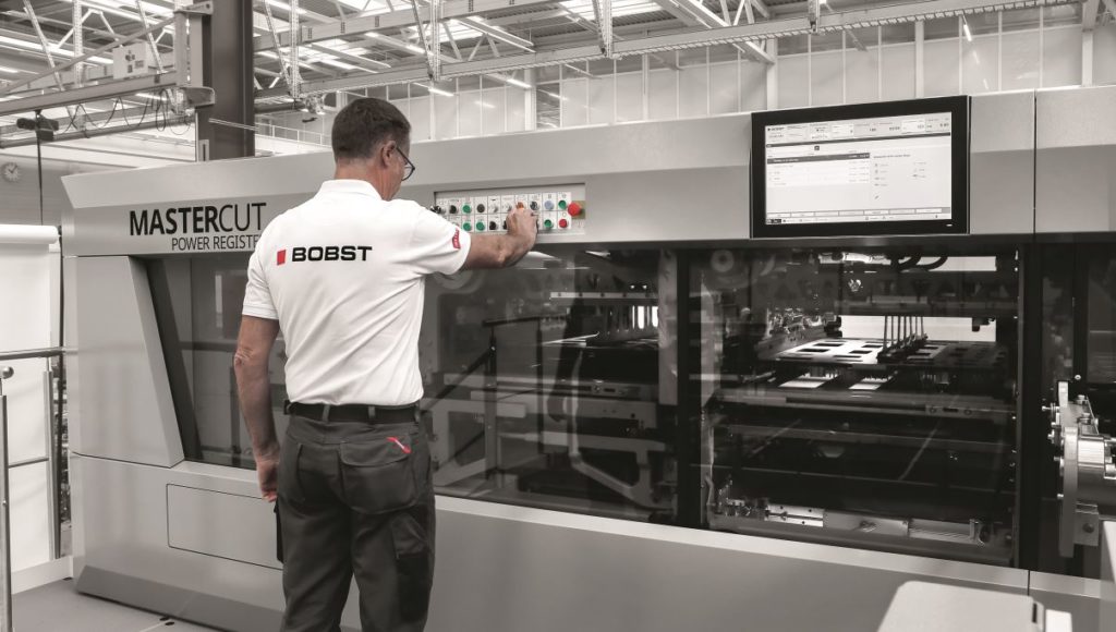 Bediener an Maschine von Bobst kontrolliert den Stanzprozess