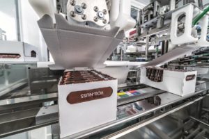 Ein Roboter verschließt einen Karton mit Ritter Sport Schokoladentafeln.