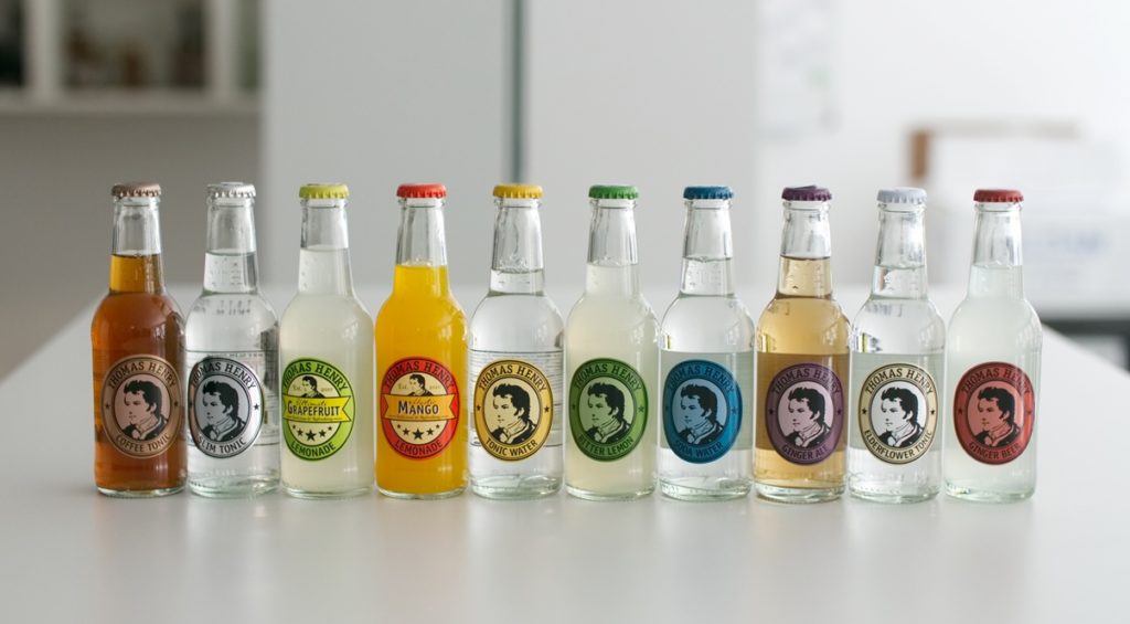 Ein Reihe von Glasflaschen mit verschiedenen Getränken von Thomas Henry