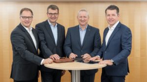 Die vier Geschäftsführer des Unternehmens Packservice stehen an einem runden Tisch