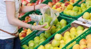 eine Frau packt Obst in Plastikbeutel