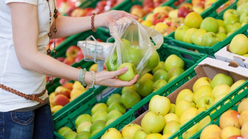 eine Frau packt Obst in Plastikbeutel