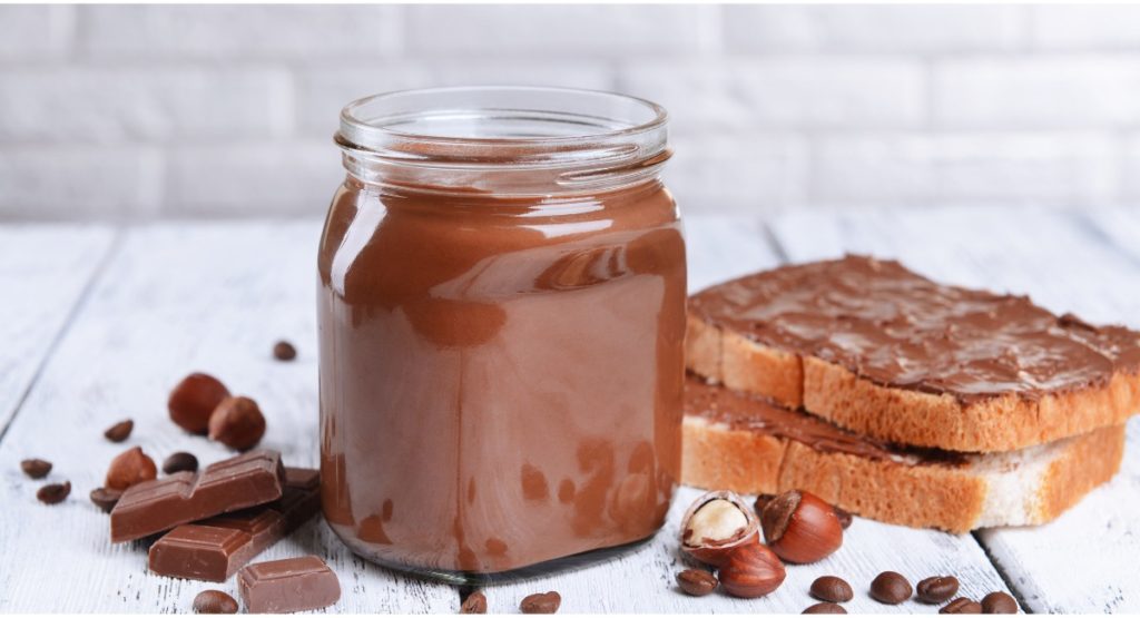 Nutella-Glas mit Brot und Schokolade und Nüssen