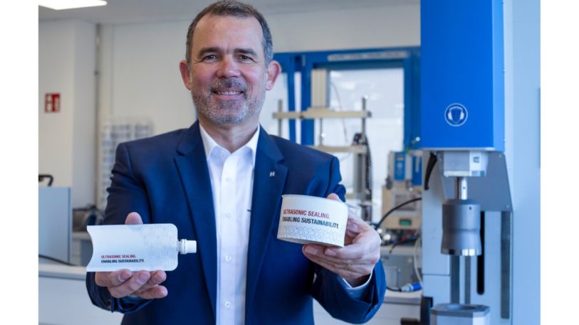 Ein Mann hält eine Tube und einen Becher aus papierbasiertem Material per Ultraschallsiegeln verschlossen