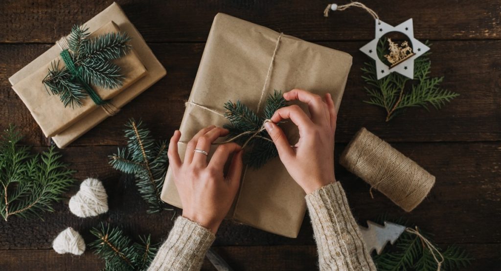 Frau packt Weihnachtsgeschenke in Recyclingpapier ein