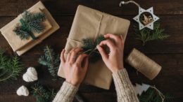 Frau packt Weihnachtsgeschenke in Recyclingpapier ein