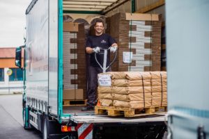 Mann auf LKW-Ladefläche mit beladenem Hubwagen