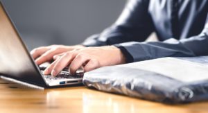 Laptop mit Händen und Plastikverpackung Retourenflut