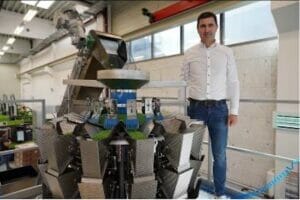 Markus Stockhammer steht in der Produktion neben einer Mehrkopfwaage von Ishida, die Silikon- und Elastomerteile sortiert und wiegt.