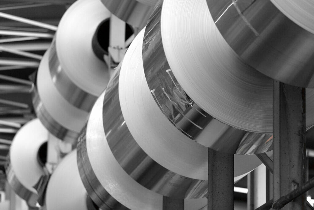 Large rolls of aluminium foil are stored in a warehouse for further processing and can be seen in the profile.