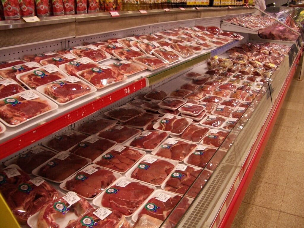 Blick auf ein Kühlregal im Supermarkt mit abgepackten Fleischprodukten, die häufig Catch-Weight-Artikel sind.
