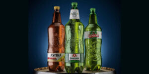 Drei verschiedene Bierflaschen stehen auf einem Fass.