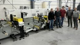 Bild von fünf Männern in einer Produktionshalle vor einer Maschine.