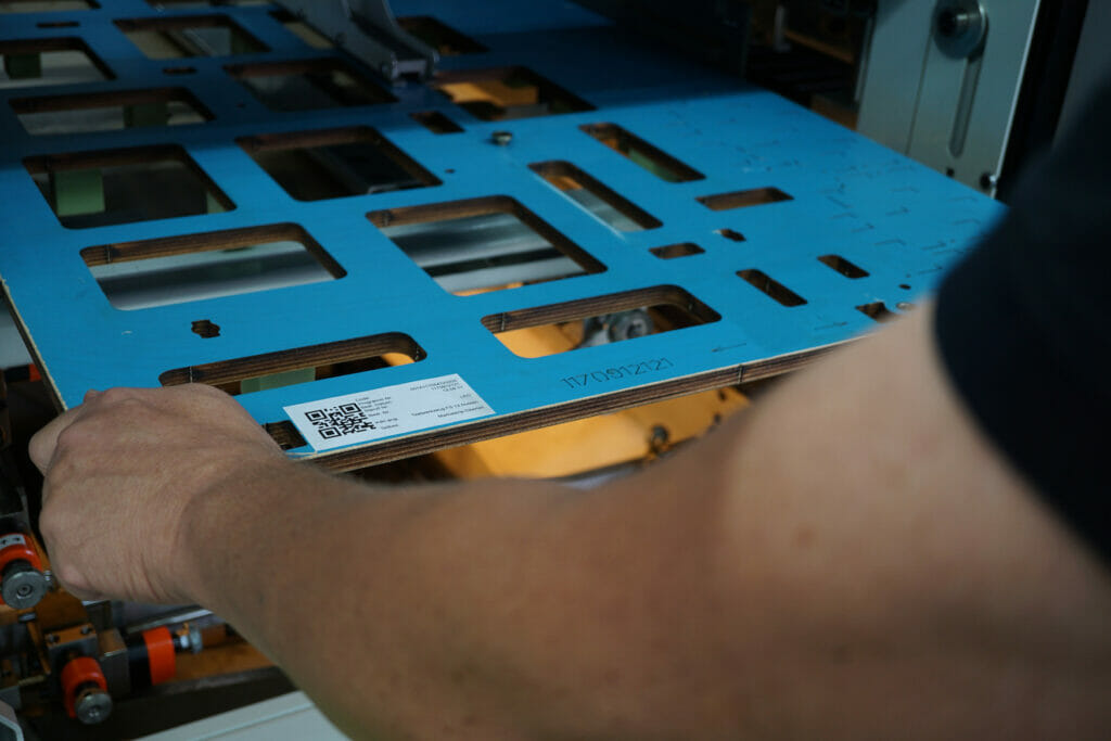 Bild von einem Arm und einer Hand, die eine blaue Stanzform hält.