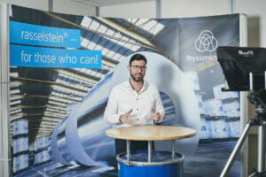 Ein Mann steht an einem Tisch und führt ein Interview.