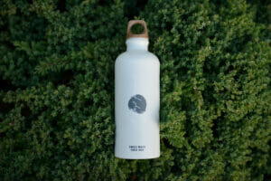 Weiße Sigg-Flasche liegt auf einer grünen Moos-Wiese.