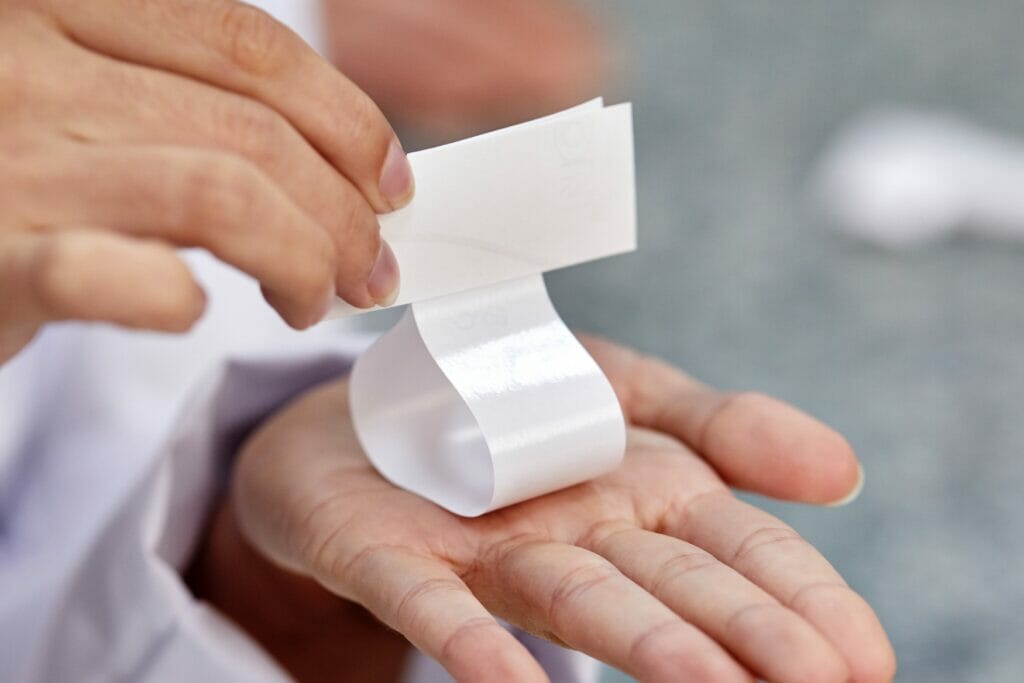 Hände halten ein gefaltetes Etikett.