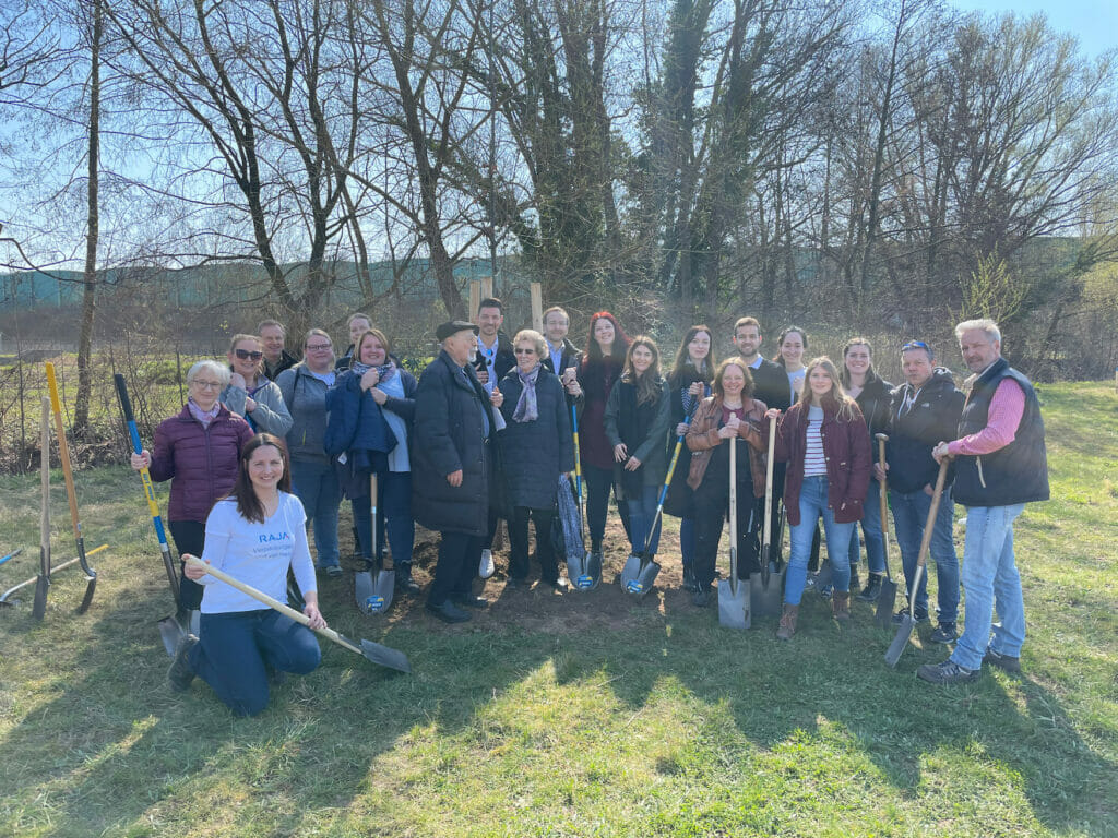 Gruppenbild von Menschen mit Schaufeln, die zum Tag des Baumes junge Bäume pflanzen.
