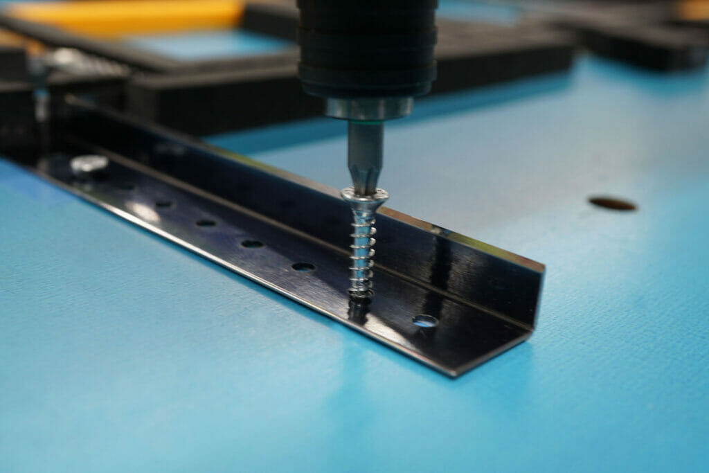 Bild von einer Metallplatte, einem Abfalltrennmesser, dass mit einer Schraube befestigt wird.