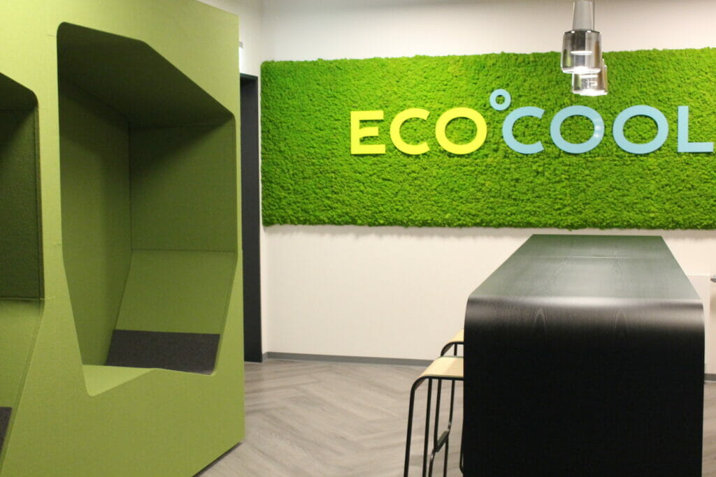 Bild von einem Raum mit einer grünen Wand, einem Tisch mit Stühlen und dem Logo der Ecocool GmbH.