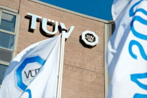 Bild von einem Gebäude des TÜV Süd mit Logo und Flaggen.