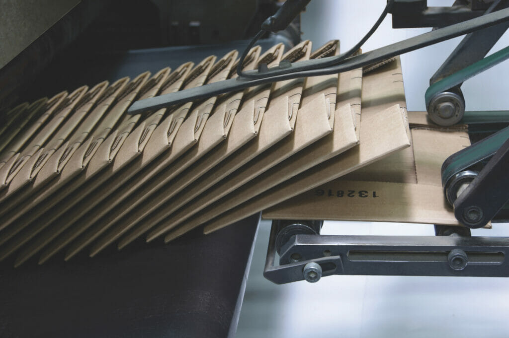 Bild einer Maschine und gefalteten Kartons aus Wellpappe