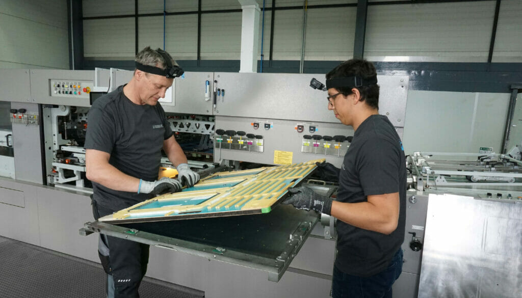 Zwei Männer mit Kopflampen arbeiten an einer Maschine.