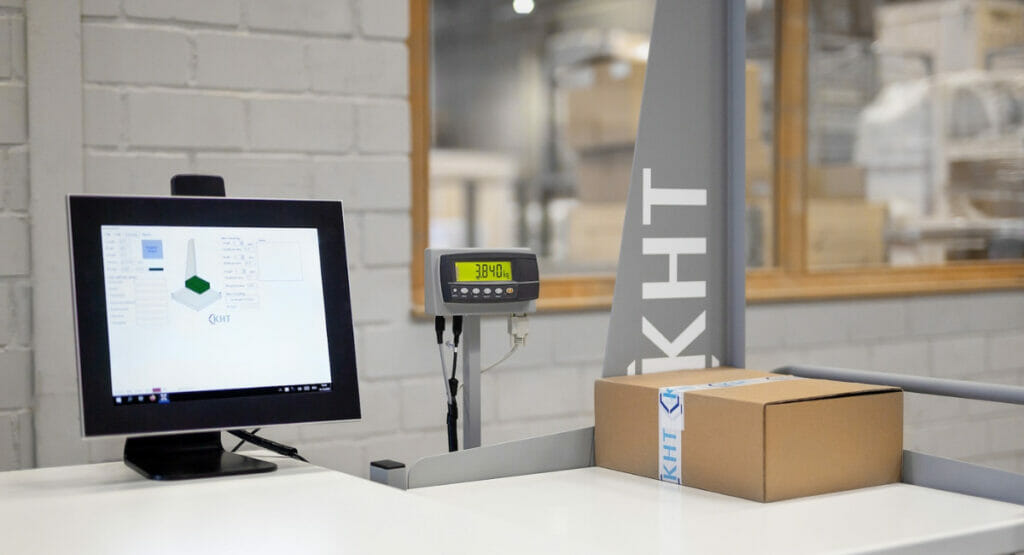 Bild von einem Tisch, auf dem ein Bildschirm, ein Scanner und ein Paket stehen.