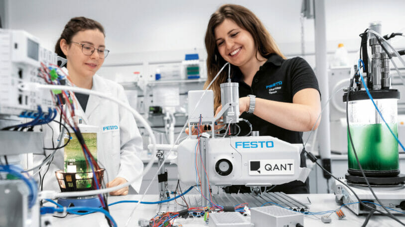 Bild von einem Labor, in dem zwei Frauen an Maschinen arbeiten.