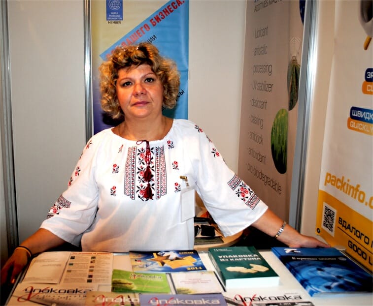 Image of a woman standing at a table with books and looking into the camera