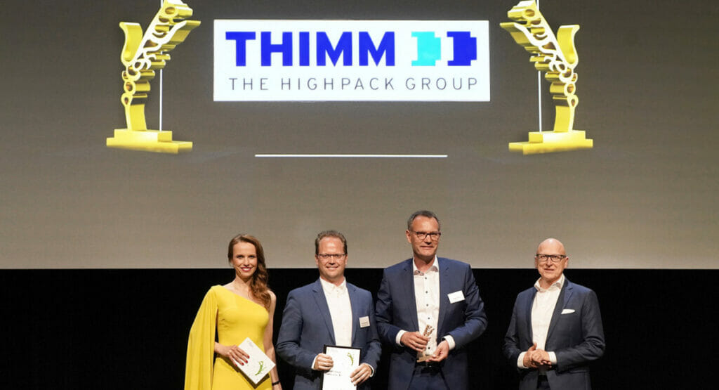 Bild von einer Frau und drei Männern, die bei einer Preisauszeichnung auf einer Bühne stehen.