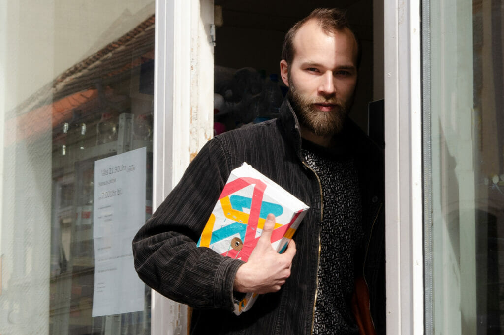 Bild von einem Mann, der durch eine Tür geht und ein Paket in der Hand hält