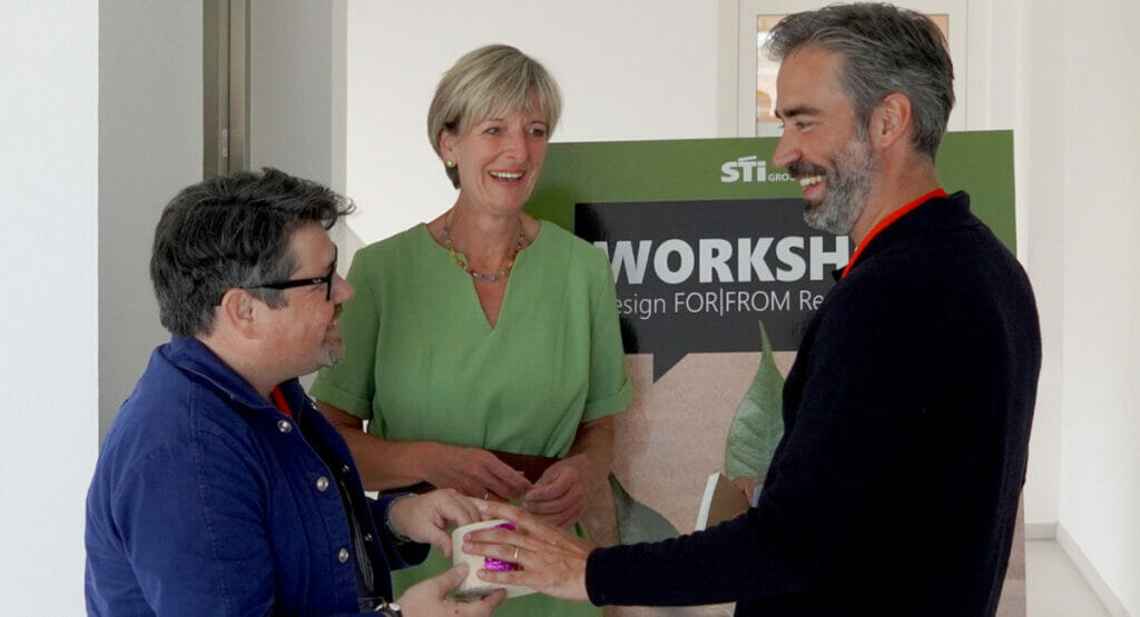 Bild von einer Frau und zwei Männern, die sich einen Gegenstand ansehen