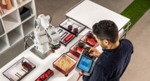 Bild von einem Mann, der an einem Tisch mit einem Roboter arbeitet.