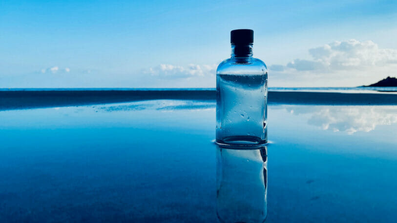 Bild von einer Glasflasche, die an einem Strand im Wasser steht