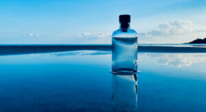 Image of a glas bottle standing in the water of the ocean.