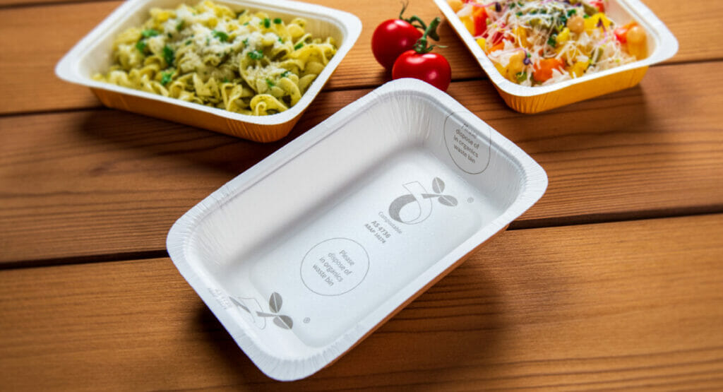 Picture of three paper trays for ready meals. Two of them are filled with food and one is empty.