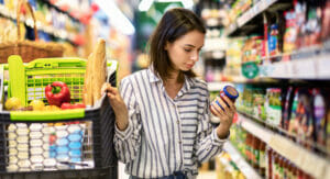 Bild von einer Frau, die in einem Supermarkt einkauft und sich Produkte ansieht.