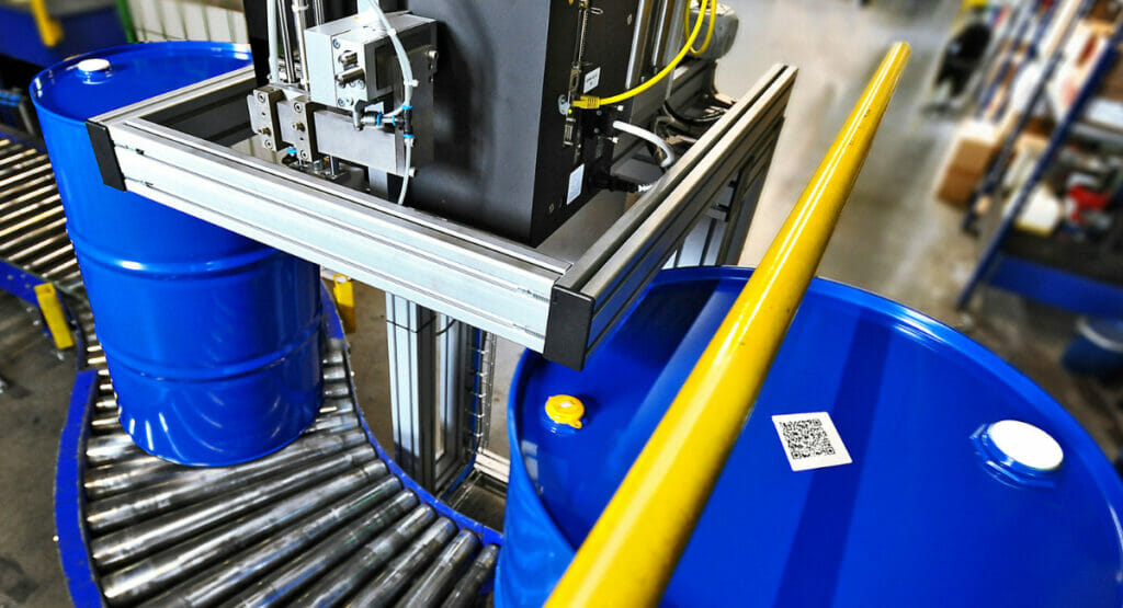 Bild von einer Verpackungsanlage mit Fässern, die mit einem QR-Code ausgezeichnet sind.