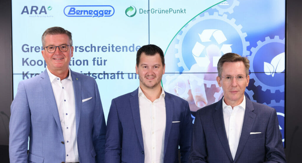 Bild von drei Männern vor einer Wand Firmenlogos