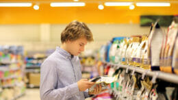 Bild von einem jungen Mann, der sich in einem Supermarkt Produkte ansieht.