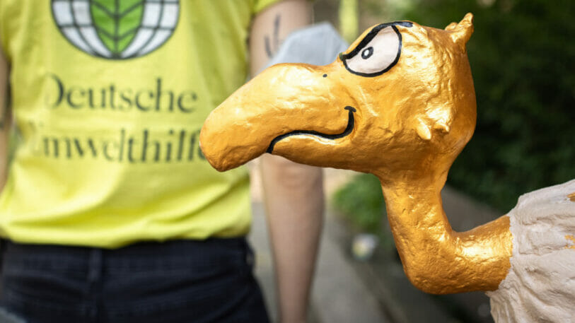 Bild von einem goldenen Geier aus Pappmasche und einem gelben T-Shirt mit dem Logo der Deutschen Umwelthilfe