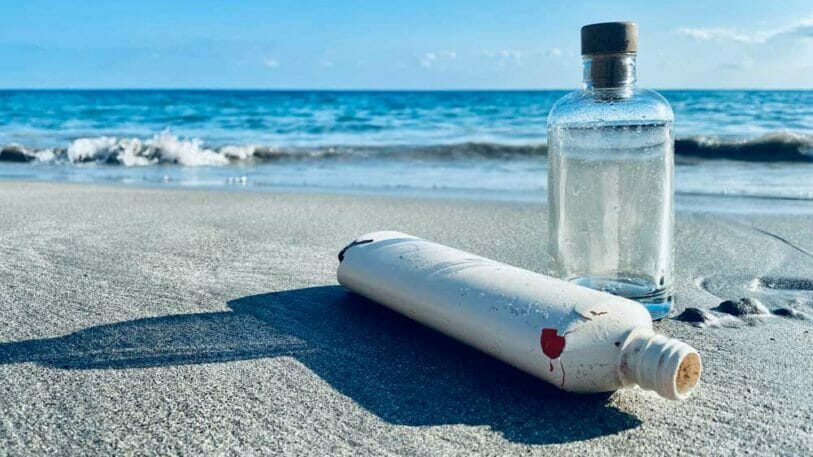 Bild von einer Aluminium- und einer Glasflasche, die am Meer liegen