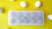 Bild von einer mit Eiern gefüllten Kunststoffbox und losen weißen Eiern.