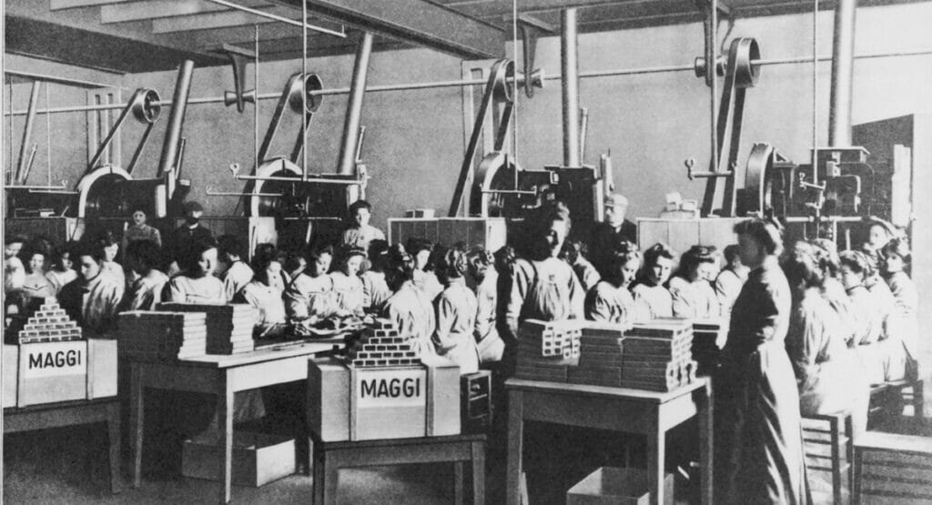 Schwarz-weiß-Aufnahme von Mitarbeitern und Mitarbeiterinnen im Werk von Maggi beim Verpacken von Maggi Suppen